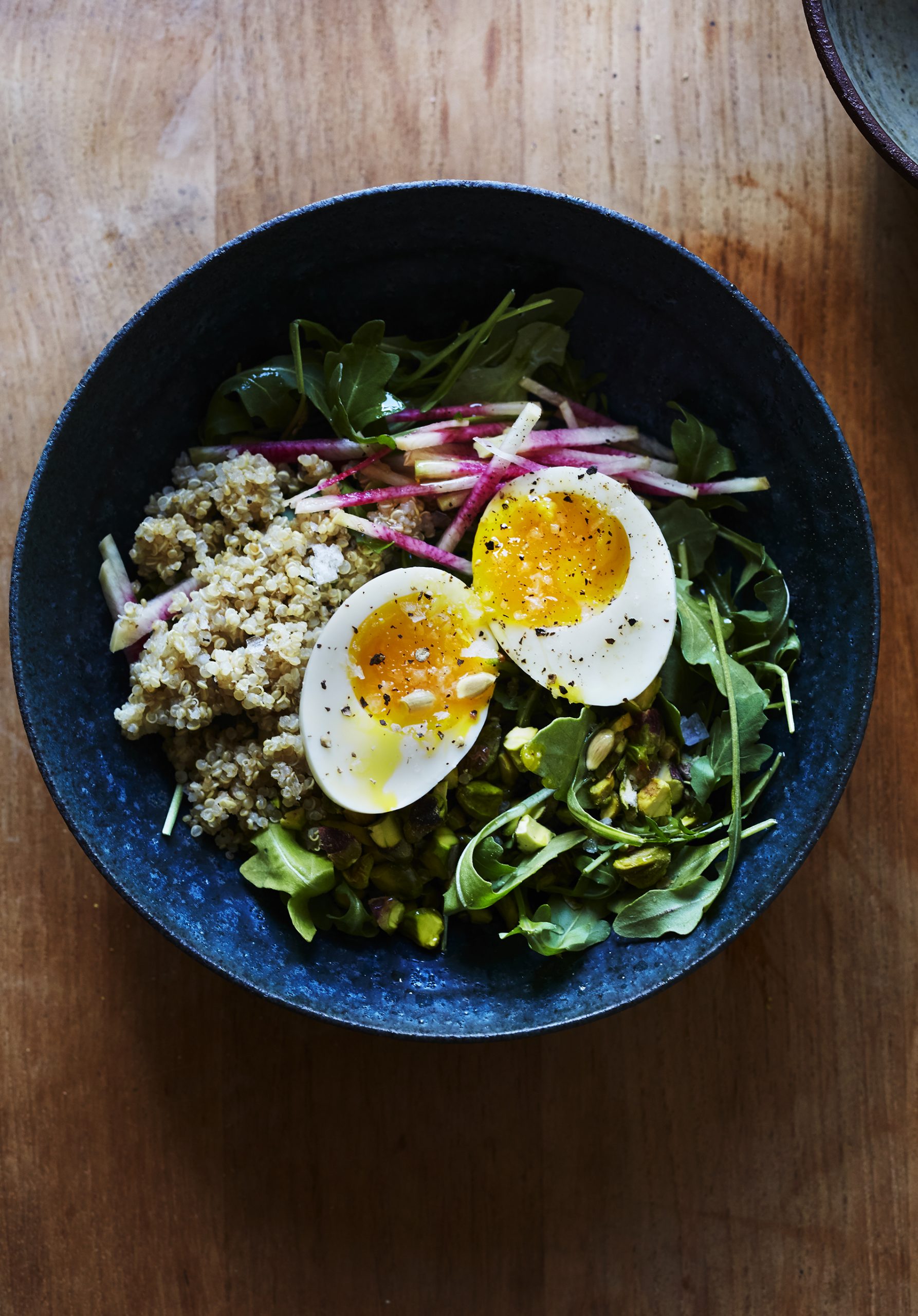 Ensalada de desayuno de rúcula con pistacho tostado, rábano y huevos blandos