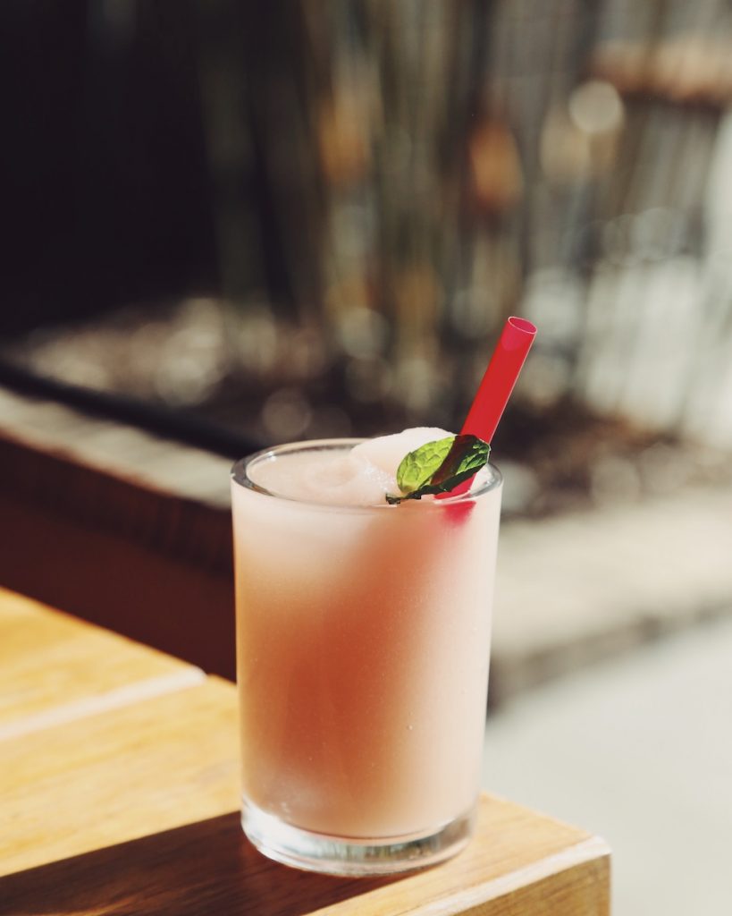 Glass of frosé on table with mint sprig and red straw.