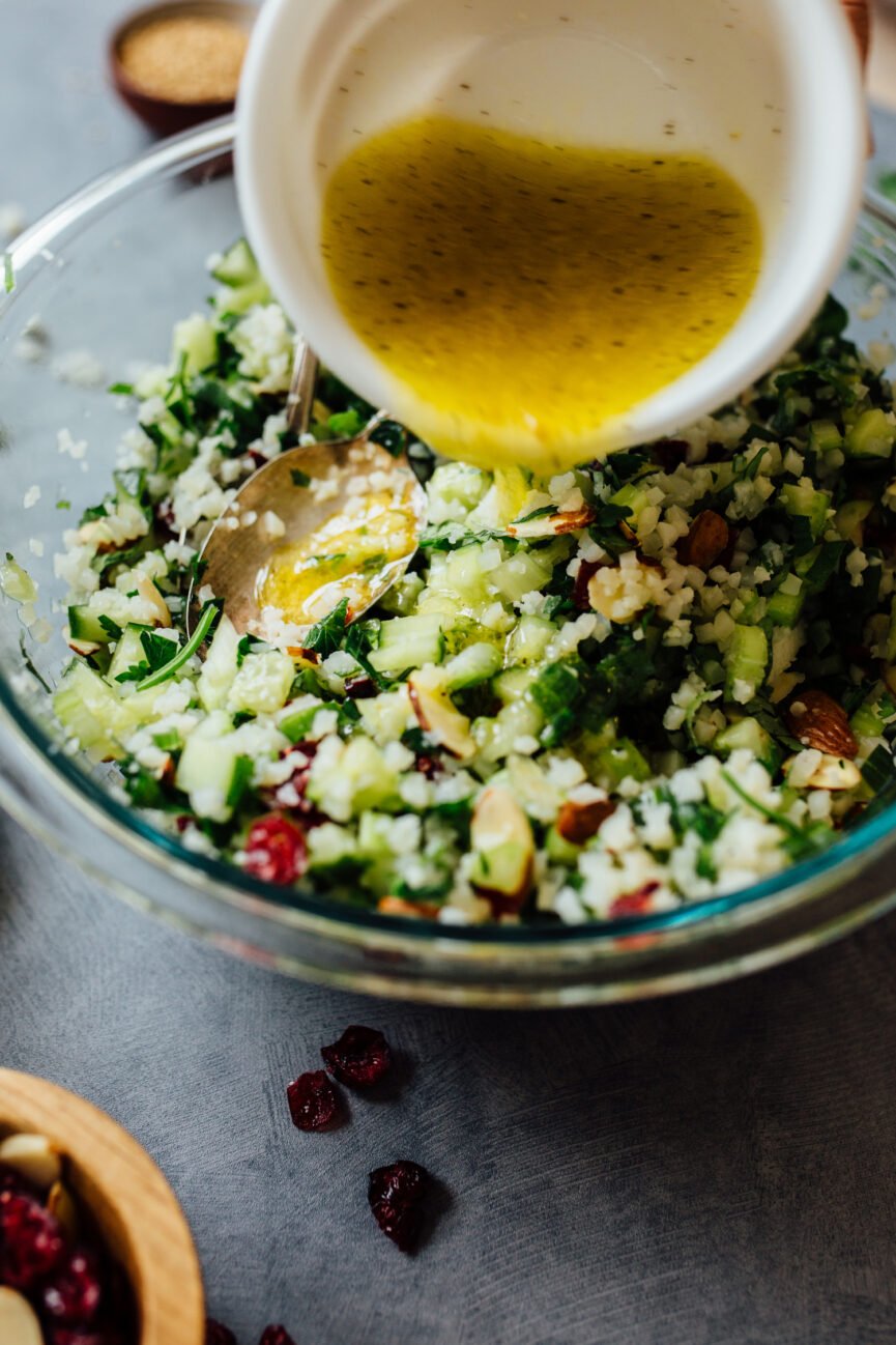 pouring dressing on cauliflower tabbouleh