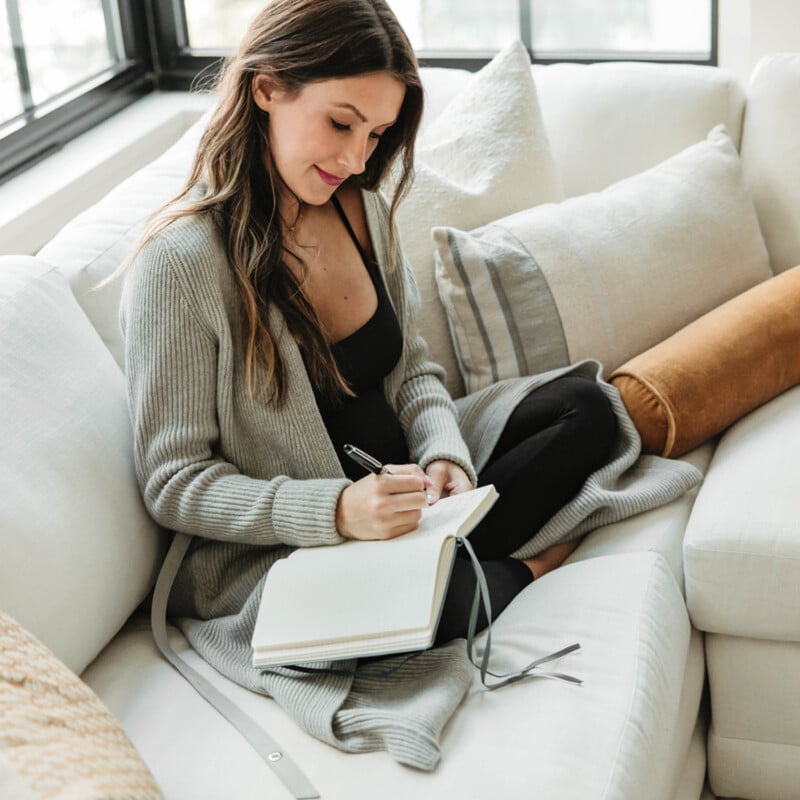 Woman journaling on couch.