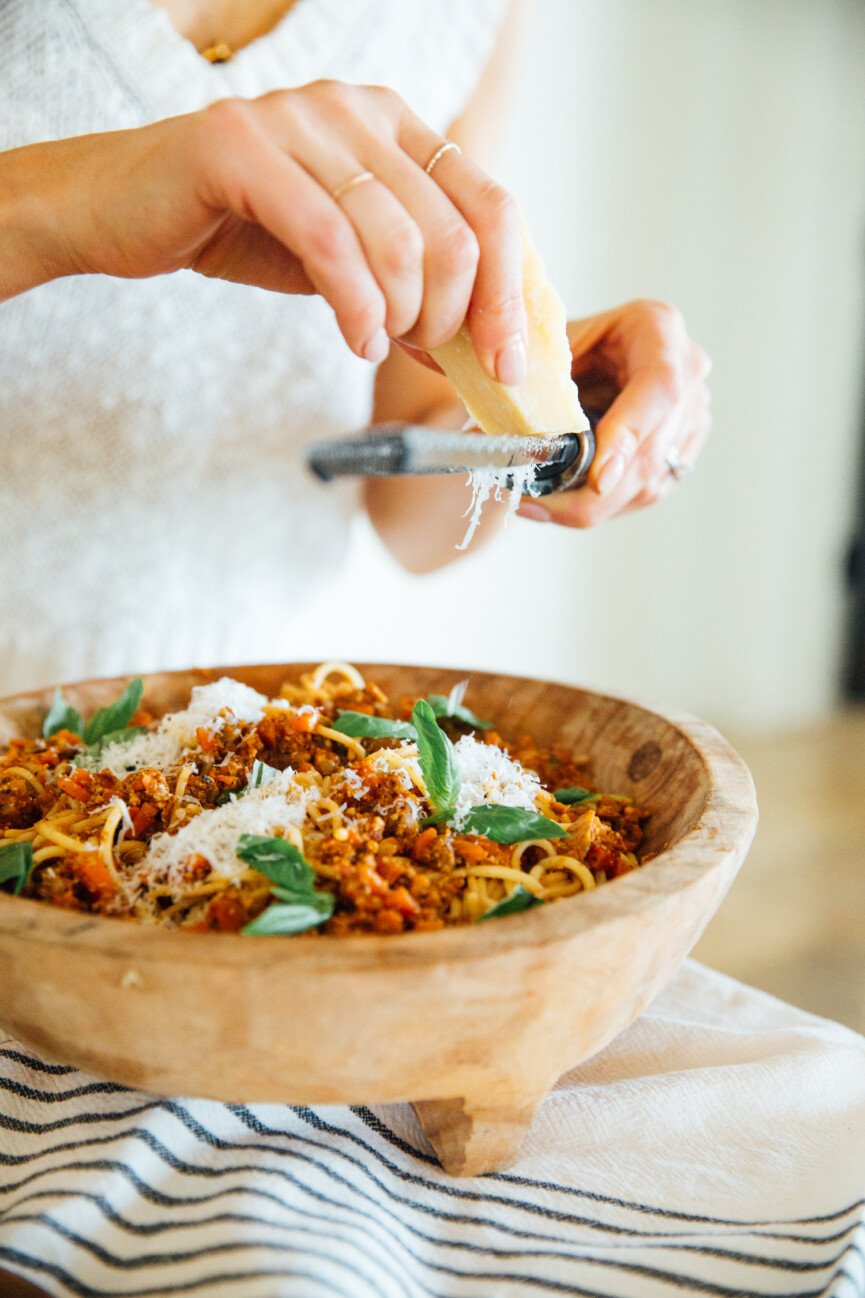 grating parmesean cheese over vegetarain bolognese