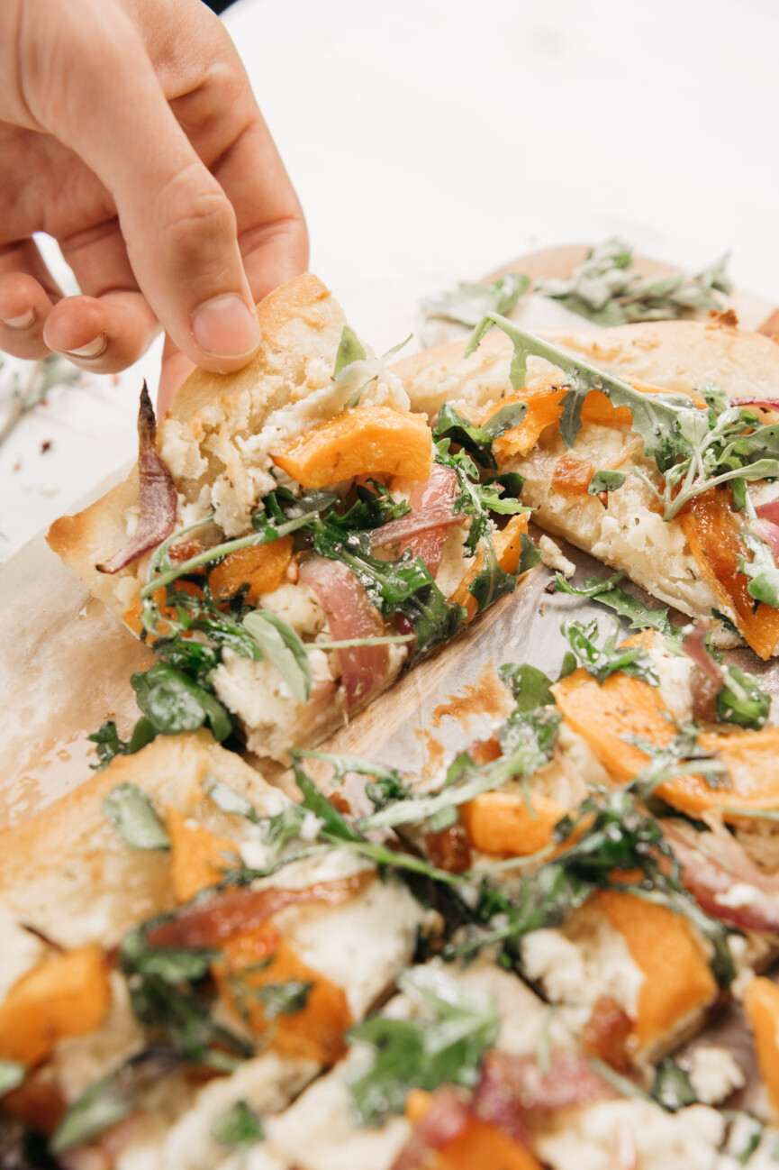 grabbing a sliced of butternut squash flatbread