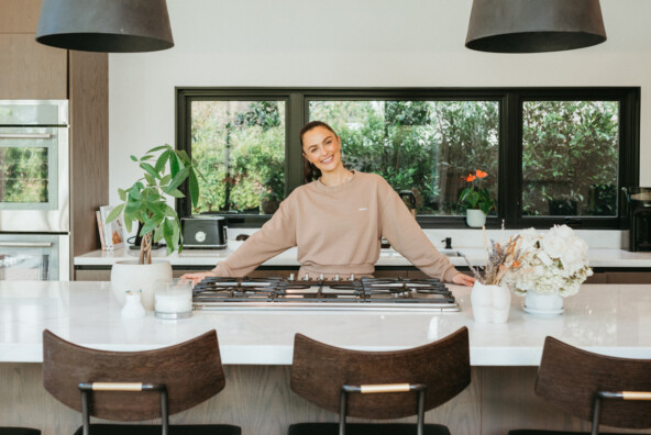 Megan Roup wearing tan sweatsuit standing at kitchen counter.