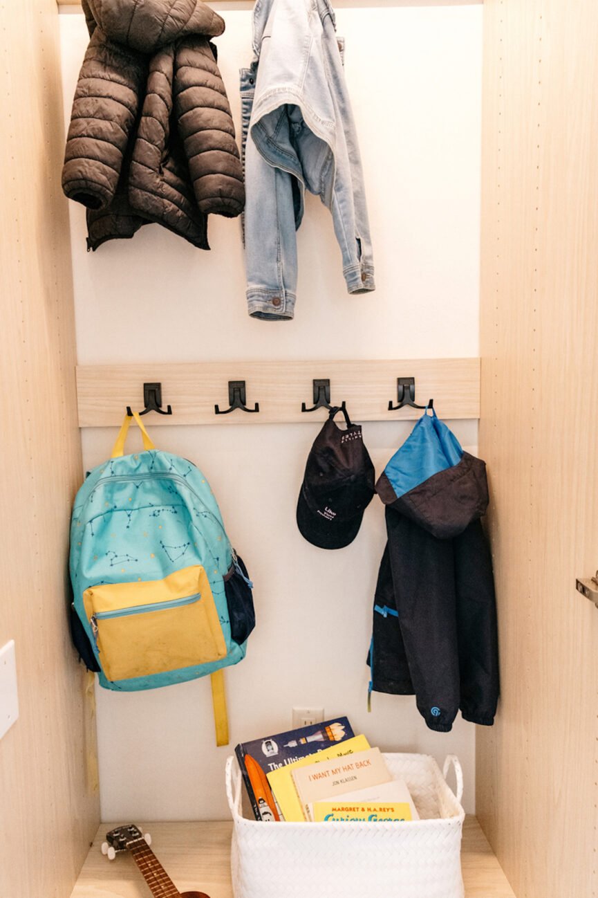 Clothes hang on hooks in the mudroom closet.