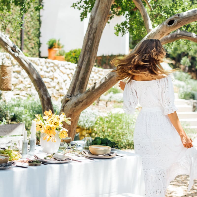 summer table setting ideas, Camille Styles summer dinner party table in backyard with trees, dancing, dance, twirling