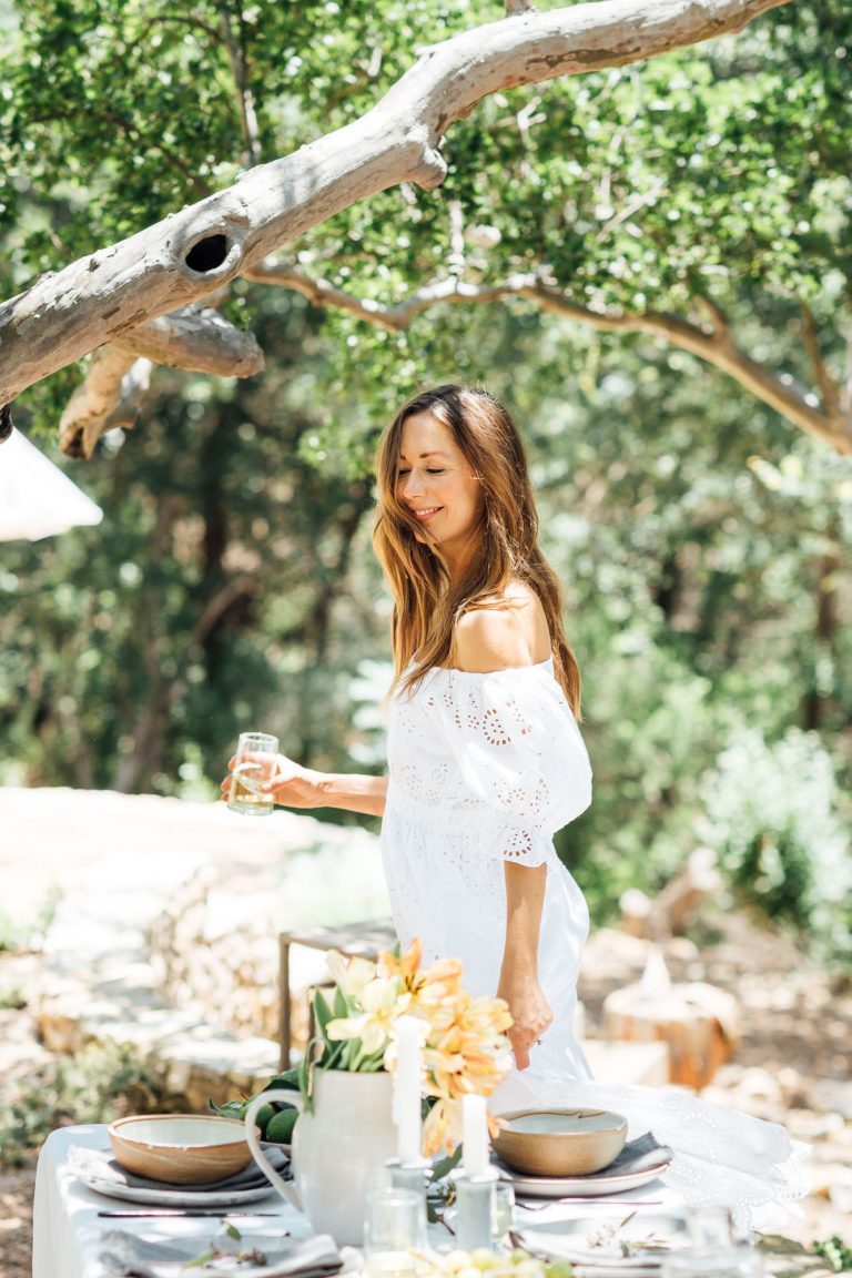 Summer table ideas, Camille Styles summer dinner table in the back yard with trees, white dress