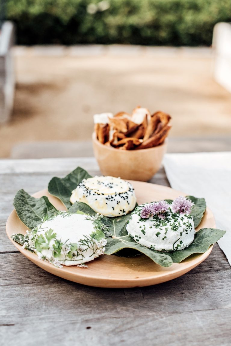 goat cheese plate garnished with edible flowers and herbs, appetizer