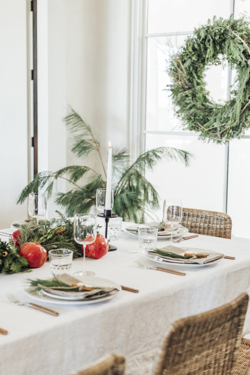 Christmas table setting - a Scandinavian holiday table with green leaves and pomegranates