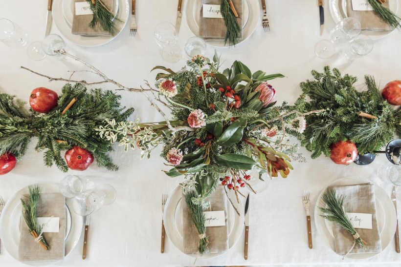 Christmas table ideas — holiday table with evergreen leaves and pomegranate