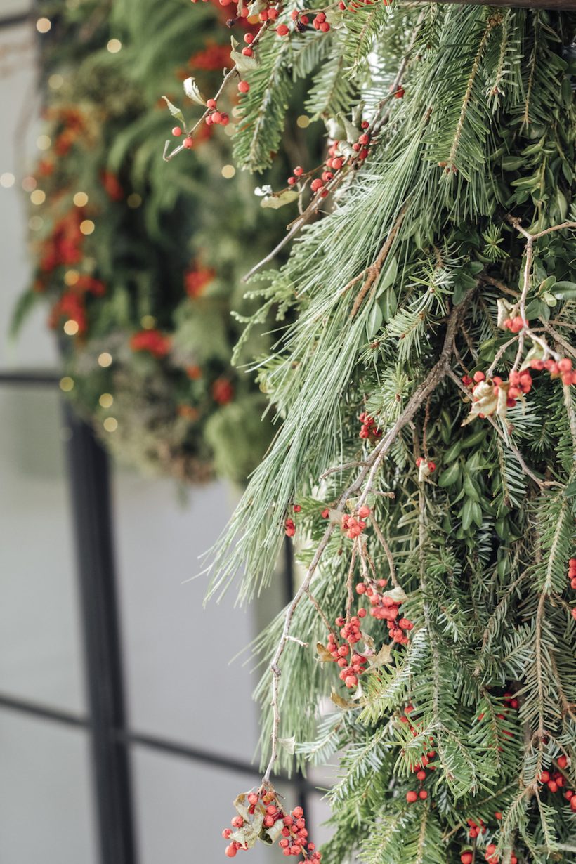 Evergreen Christmas wreath and wreath with red fruits on the front door, on the threshold of the best holiday decoration, how to make a Christmas wreath and wreath