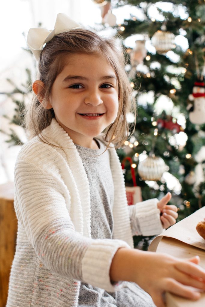 Girl smiling while decorating cookies at gingerbread making party - ways to give back during the holidays