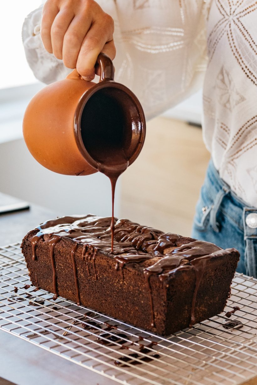 camille style in the kitchen pouring glaze over chocolate cake