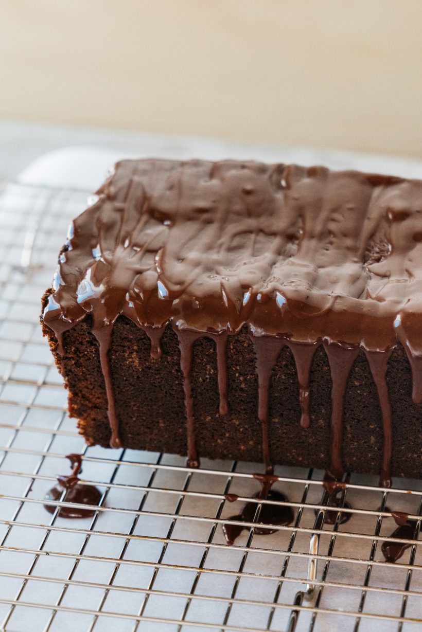 camille style in the kitchen pouring glaze over chocolate cake