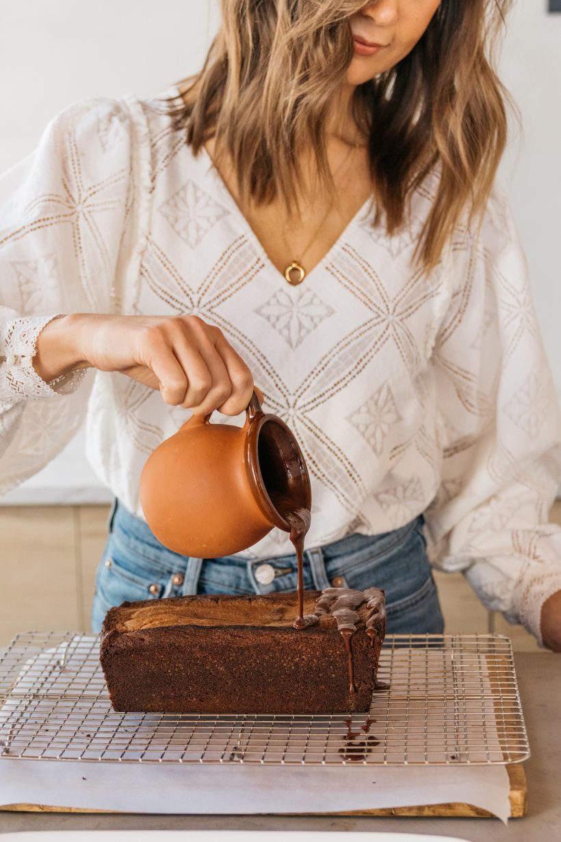 camille style in the kitchen pouring glaze over chocolate cake