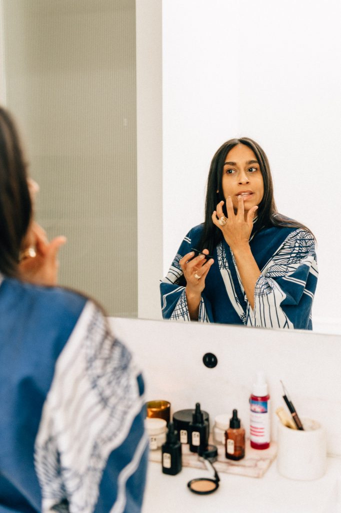 Shani Van Breukelen applying lip balm in her New York City apartment bathroom_how to heal pcos naturally