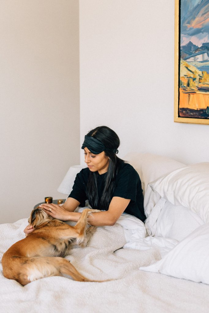 Shani Van Breukelen petting her dog in bed_best affordable luxury sheets