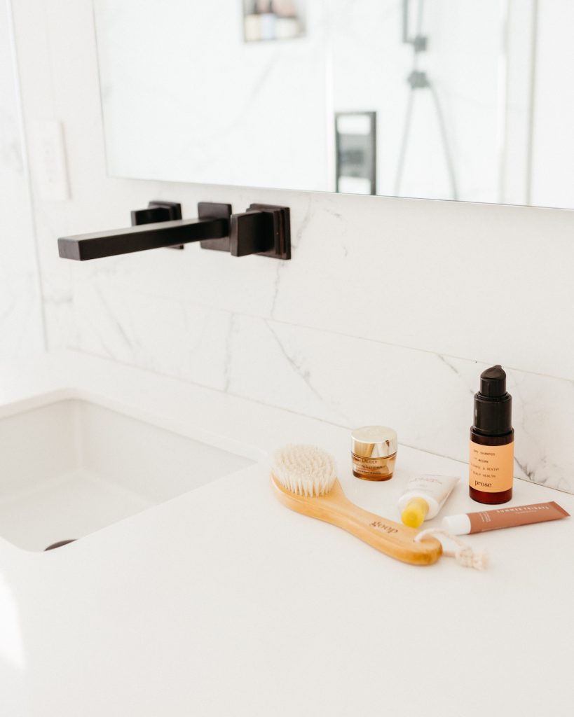 Megan Roup's bathroom sink with various skincare products and a goop dry brush laying on the counter.