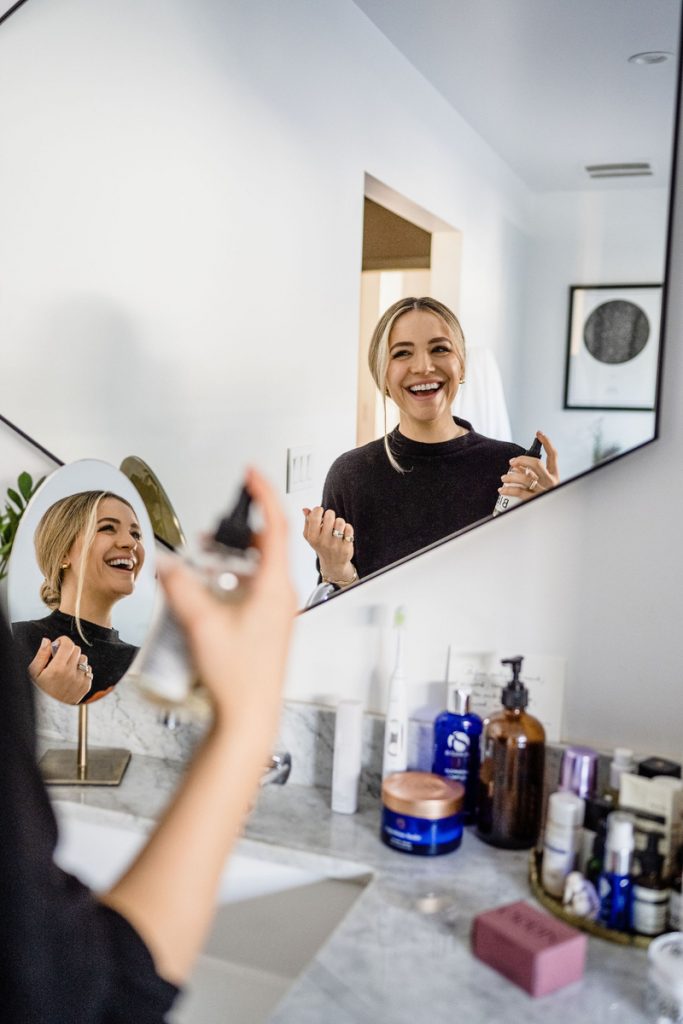 Woman smiling applying makeup at mirror