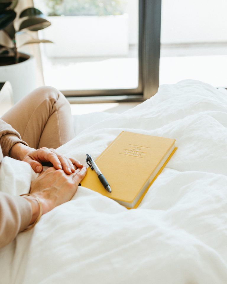 Woman's hands resting on a yellow notebook_emotional exhaustion