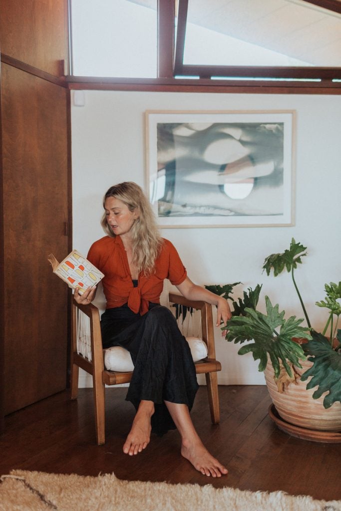 Nitsa Citrine reading a book in the living room of her Malibu beach home_sober-curious books