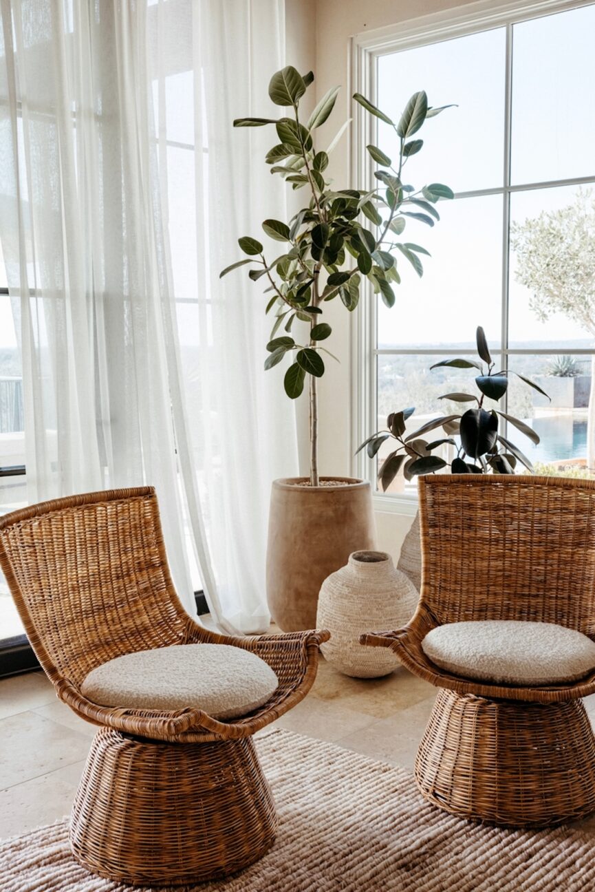 Cadeiras tecidas na sala de estar com plantas ao fundo.
