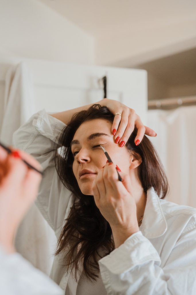 summer beauty trends eyeliner woman doing makeup in mirror