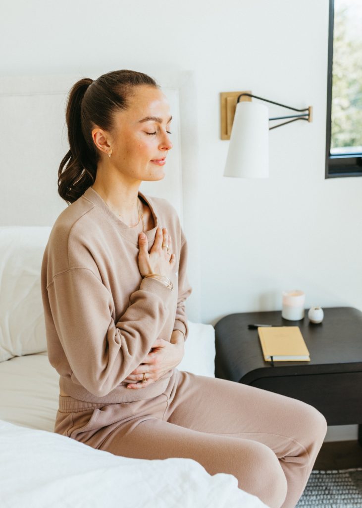 Meghan Roup meditates while sitting on bed_how to wake up easier