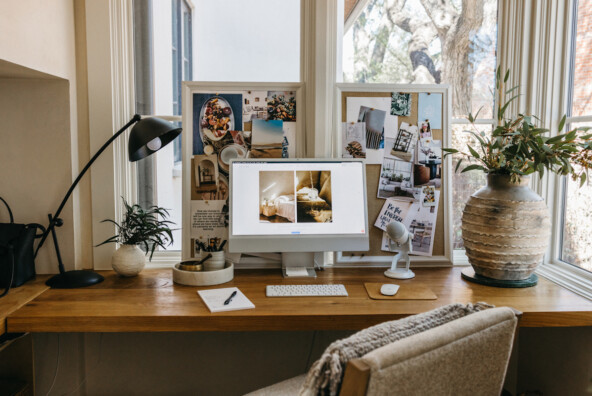 Modern desk with silver monitor in front of two vision boards.