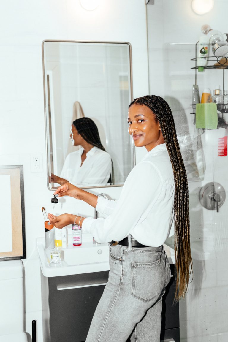 Woman applying skin care products in front of mirror