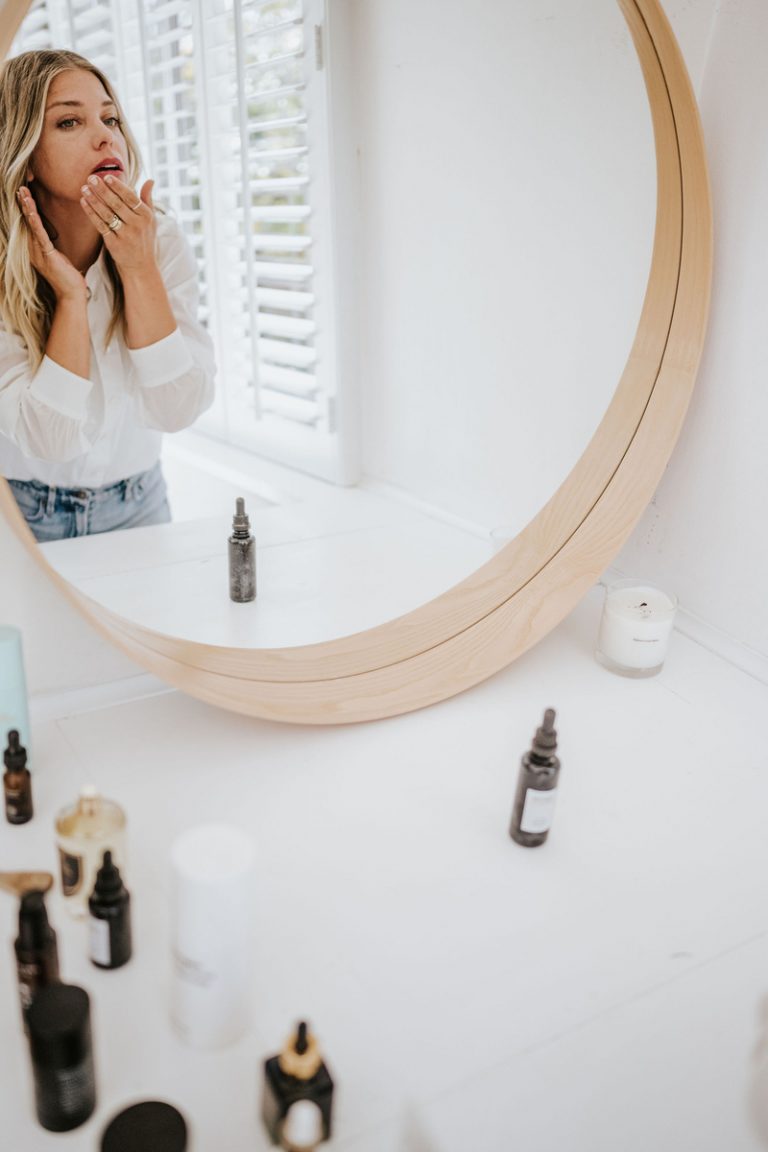 Woman applying skincare products at the mirror_bakuchiol versus retinol