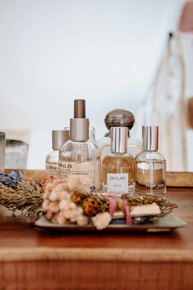 Clean fragrance brands and dried flowers on a vanity. 