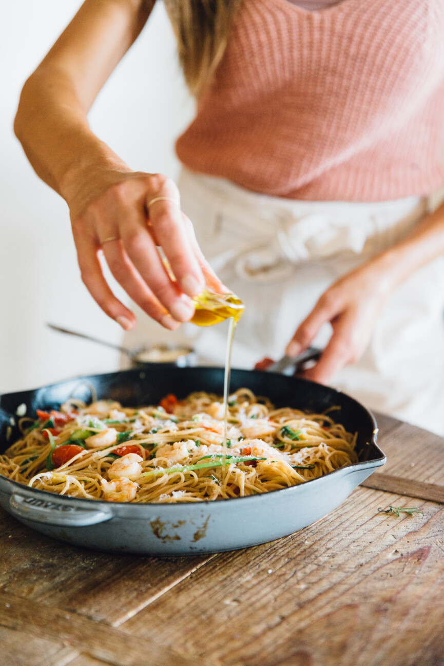 drizzling olive oil on garlic and shrimp spaghetti