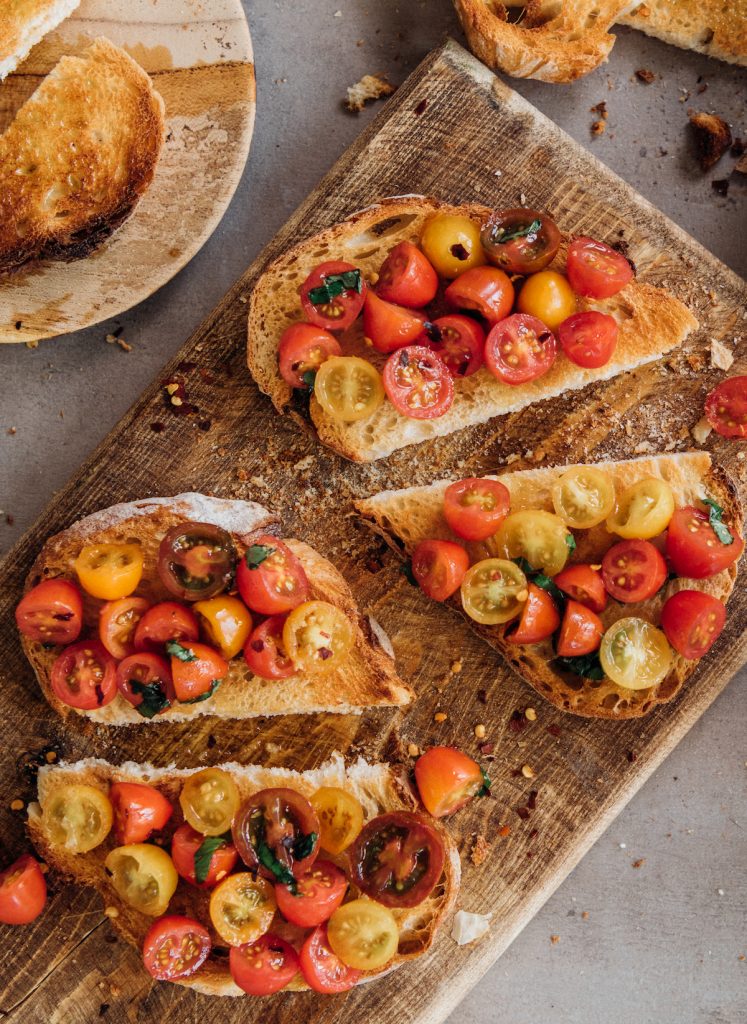 Easy tomato bruschetta on wooden serving board.