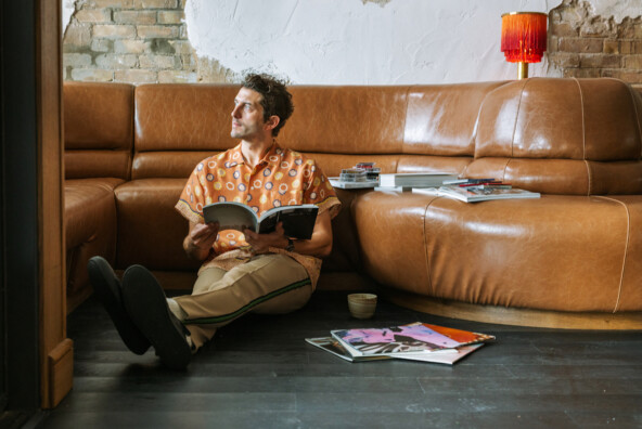 Man sitting on floor flipping through magazines.