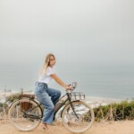 Woman biking by the ocean.