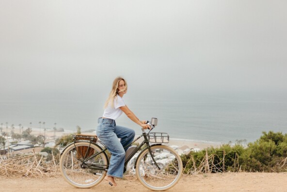 Woman biking by the ocean.