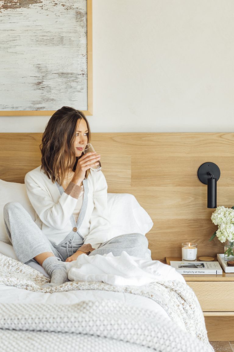 woman sitting on her white bed