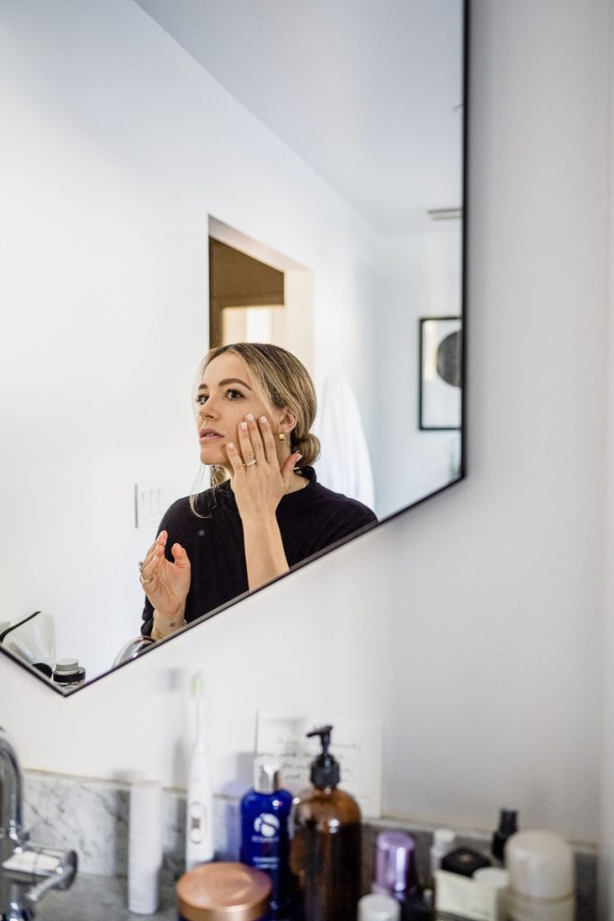 blonde woman applying skincare in mirror_best way to apply skincare