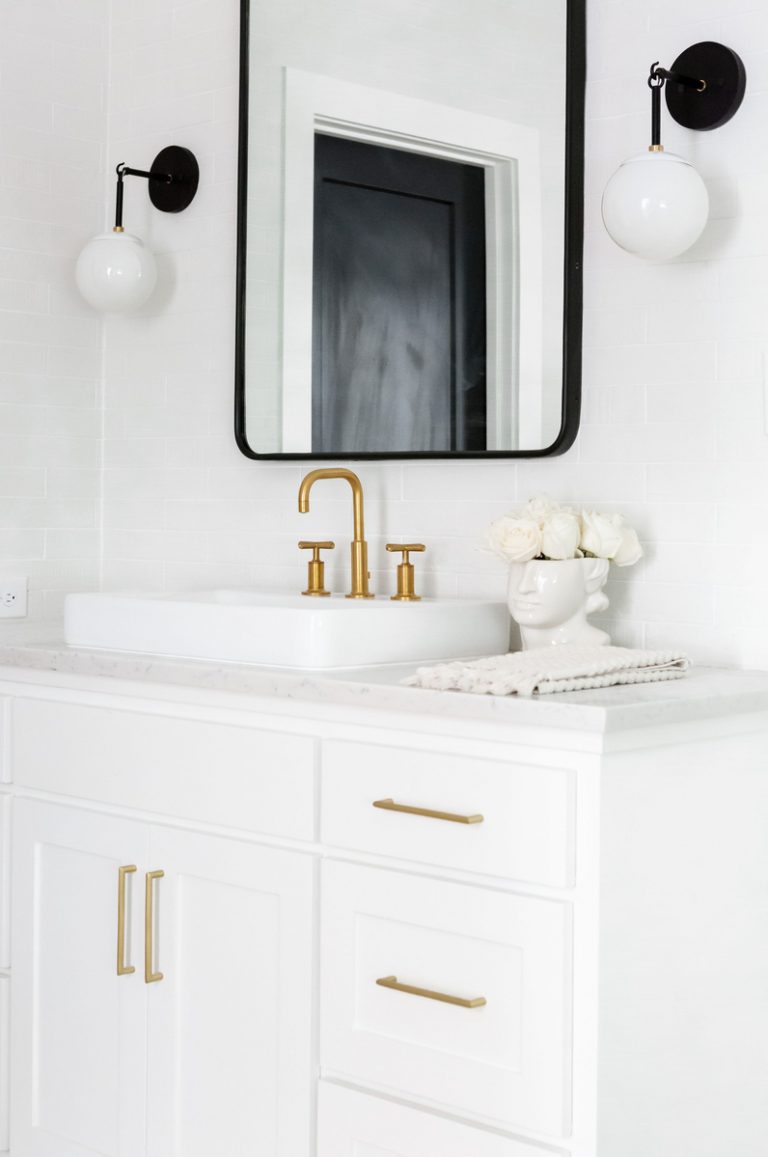 Ashley Robertson cleans up vanity in white minimalist bathroom