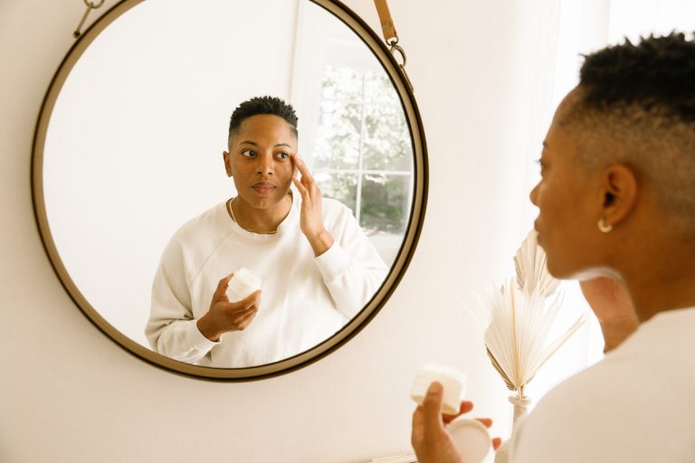femme appliquant une crème pour les yeux dans un miroir_meilleure façon d'appliquer les soins de la peau