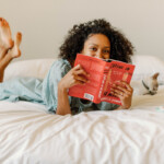 Woman reading book on bed.