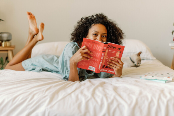 Woman reading book on bed.