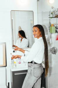 Woman applying face oils in bathroom.