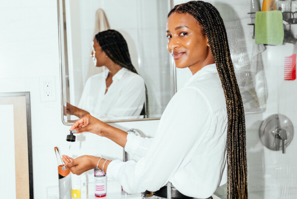 Woman applying face oils in bathroom.