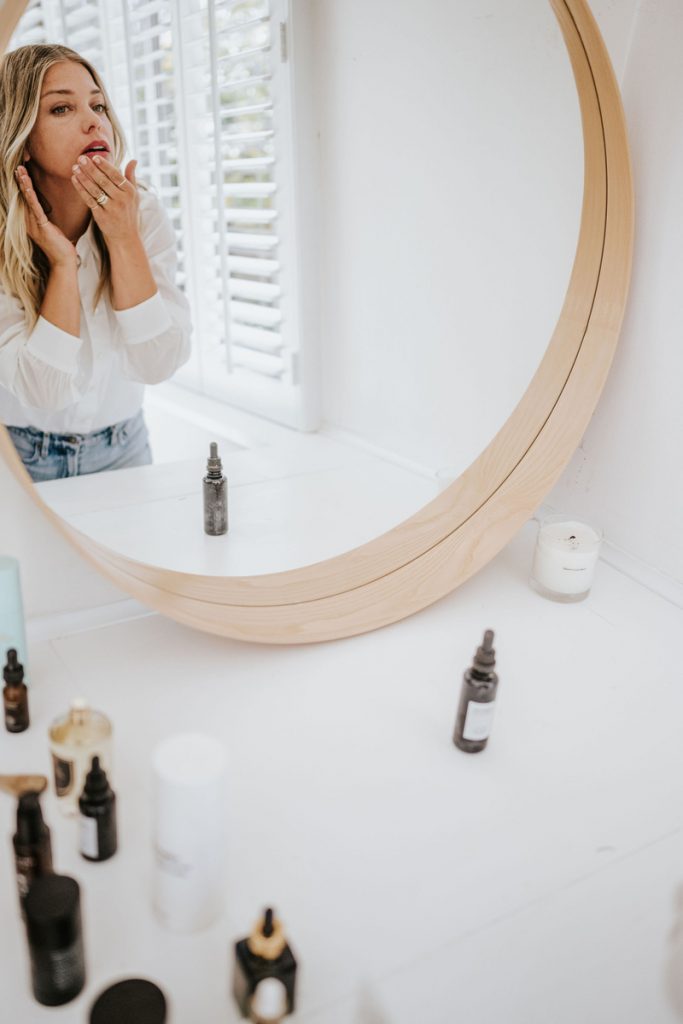 Janessa Leoné applying skincare in bathroom mirror_best aha products