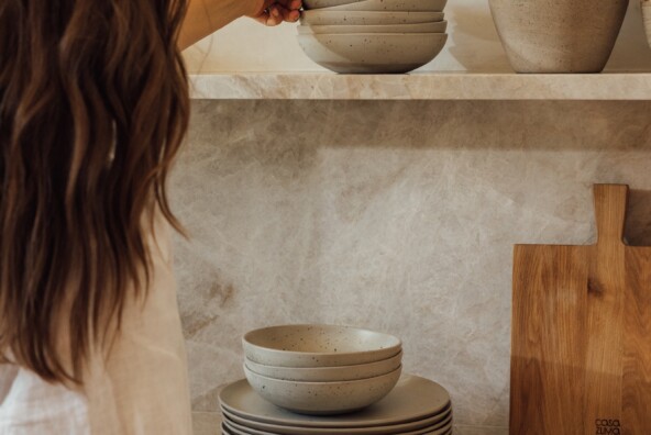 woman putting away ceramics on organized kitchen shelves