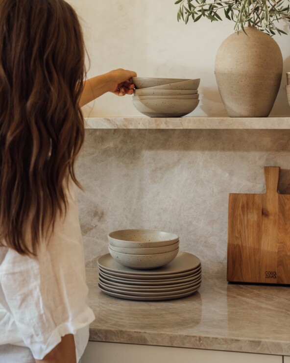 woman putting away ceramics on organized kitchen shelves