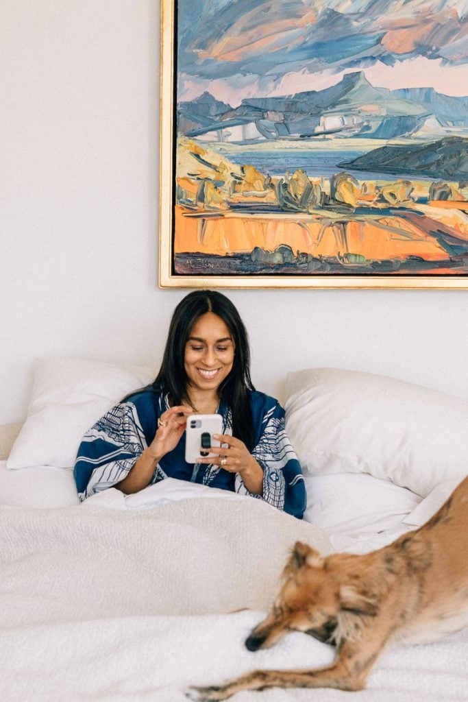 Shani van Breukelen using phone in bed with dog