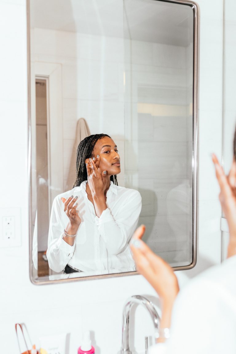 Shanika Hillocks applying serum in bathroom mirror_best anti-aging serums for 30s