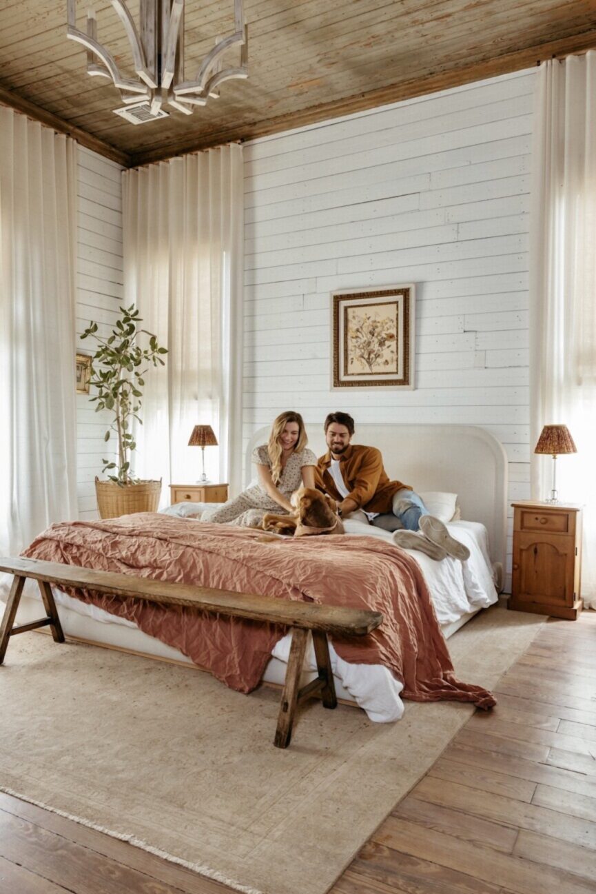 Couple sitting on bed and petting dog.